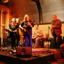 The "DoorNellies" featuring Karen Ann (acoustic guitar/vocals), Peggy Lecuyer (mandolin/vocals), Gene Lemme (bass guitar), Mike McMann (acoustic guitar/vocals), bongo player, Luke McNamee (saxophone), and Ted Hennessey performing at "Still: DQ 2 For Dick Quinn" concert held at The Hangar in Troy, NY, Sunday, October 11, 2015. Series 5/15. Photo taken by Amy L. Modesti with her Canon Rebel SL1 Digital SLR Camera. (C): Amy Modesti, 2015