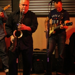 Graham Tichy (guitar/vocals, right) performing a local saxophonist at "Still: DQ 2 For Dick Quinn" concert held at The Hangar in Troy, NY, Sunday, October 11, 2015. Series 3/13. Photo taken by Amy L. Modesti with her Canon Rebel SL1 Digital SLR Camera. (C): Amy Modesti, 2015